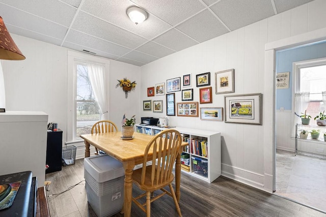 dining area featuring a wealth of natural light, a paneled ceiling, and wood finished floors