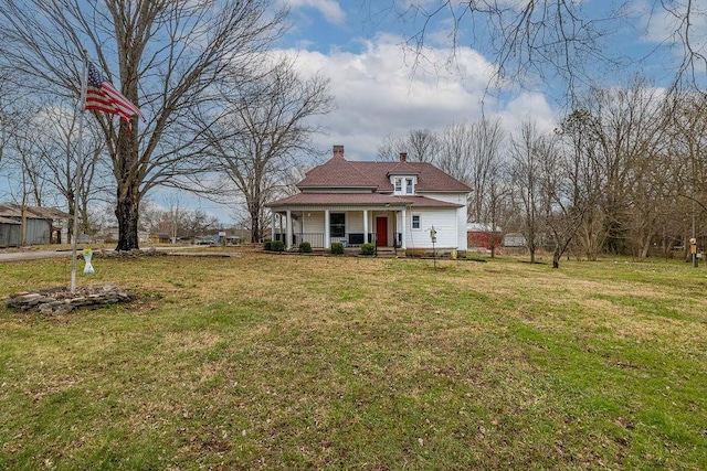 view of front of home with a chimney, covered porch, and a front lawn