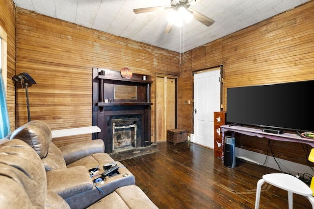 living area with a fireplace with flush hearth, wood walls, ceiling fan, and wood-type flooring