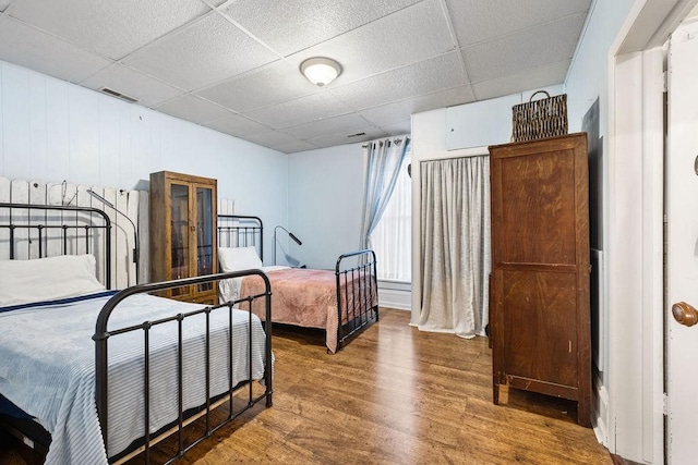 bedroom featuring visible vents, a drop ceiling, and wood finished floors