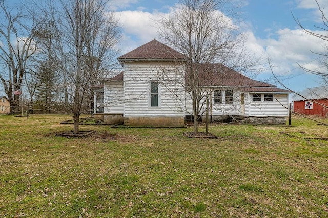 back of house with a yard and a shingled roof