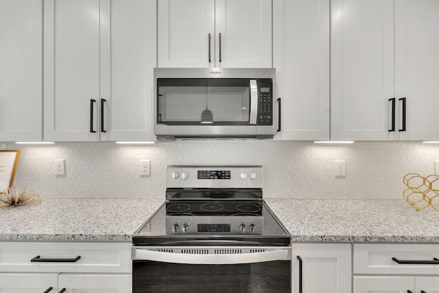 kitchen featuring stainless steel microwave, white cabinets, electric stove, and backsplash