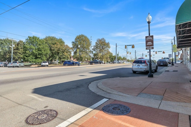 view of street featuring curbs, street lighting, traffic lights, and sidewalks