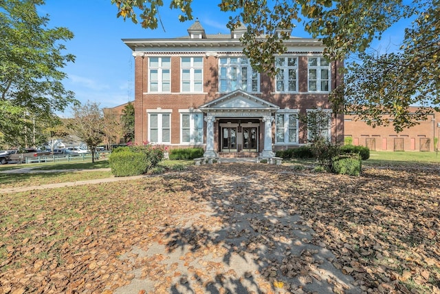 view of front of house featuring brick siding, french doors, and fence