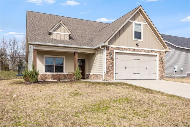 view of front of house featuring board and batten siding, concrete driveway, a front yard, roof with shingles, and stone siding