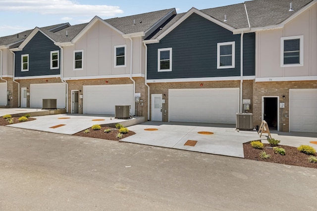 view of property with brick siding, driveway, central AC, and board and batten siding