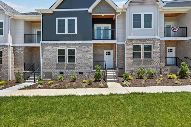 view of property featuring crawl space, brick siding, and board and batten siding