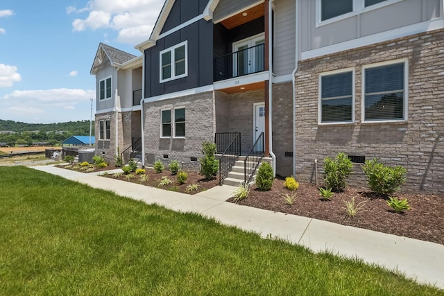 view of front facade featuring a front lawn, brick siding, board and batten siding, and crawl space