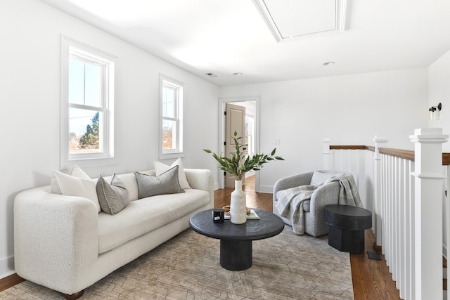 living area featuring visible vents, baseboards, attic access, and wood finished floors