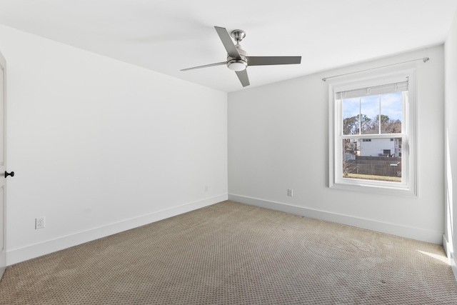 spare room with light colored carpet, baseboards, and ceiling fan