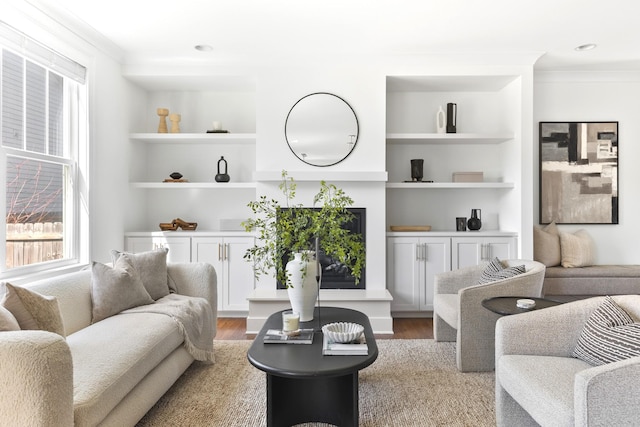 living area with crown molding, built in features, and wood finished floors