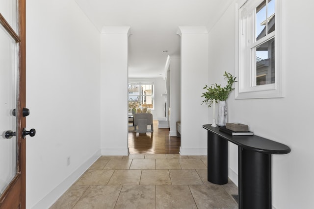 hallway with light tile patterned flooring, baseboards, and ornamental molding