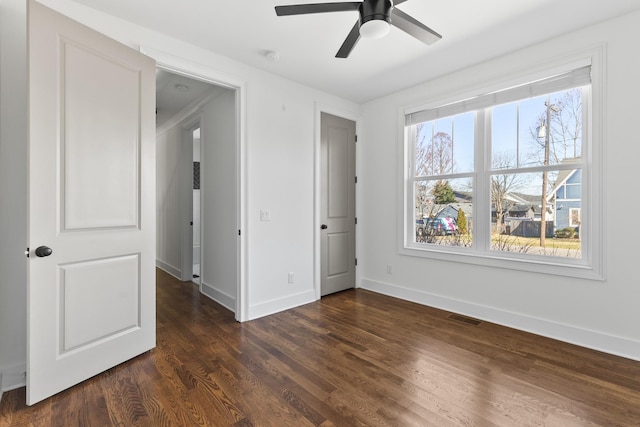 unfurnished bedroom with visible vents, multiple windows, baseboards, and dark wood-style flooring