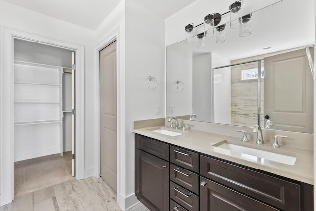 bathroom featuring a sink, a walk in closet, walk in shower, and double vanity