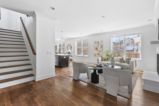 living area featuring a wealth of natural light, dark wood-type flooring, and stairs