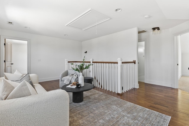 living area with attic access, wood finished floors, visible vents, and baseboards