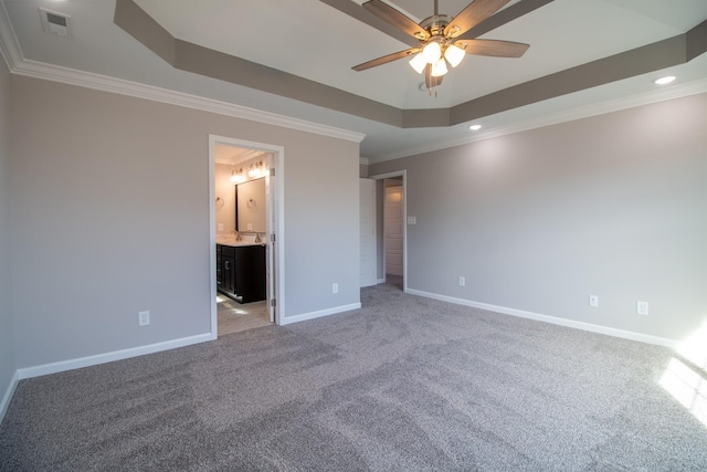 unfurnished bedroom featuring baseboards, ornamental molding, ensuite bathroom, a raised ceiling, and light colored carpet