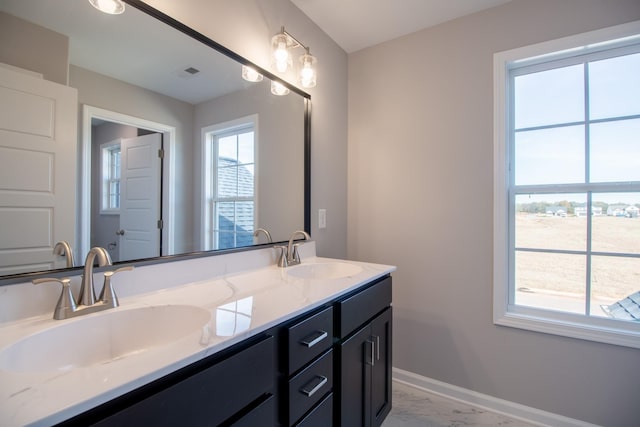 bathroom with a sink, baseboards, marble finish floor, and double vanity