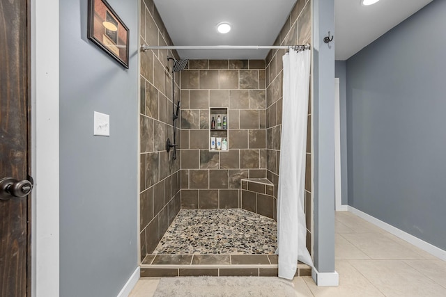 bathroom with tile patterned floors, baseboards, and tiled shower