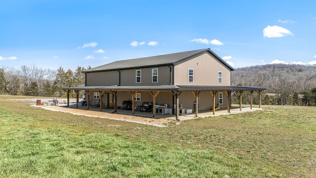 back of house featuring a lawn, metal roof, and a patio