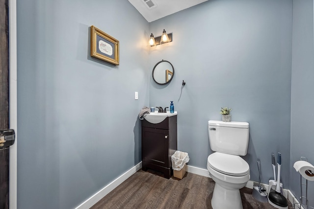 bathroom featuring vanity, toilet, wood finished floors, and baseboards