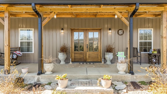 entrance to property with covered porch, french doors, and board and batten siding