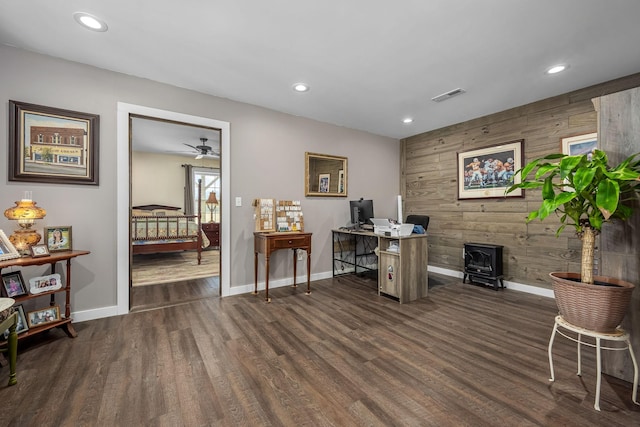 office area with visible vents, wood walls, dark wood-type flooring, and a wood stove