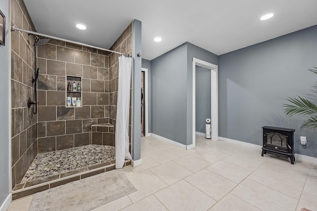 bathroom featuring baseboards, recessed lighting, tiled shower, a wood stove, and tile patterned floors