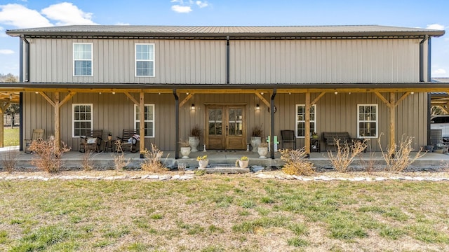 rear view of property with a patio area, board and batten siding, french doors, and a lawn