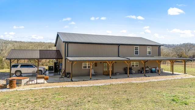 rear view of house featuring a carport, a lawn, and metal roof