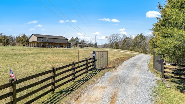 view of street with a gated entry, a rural view, driveway, and a gate