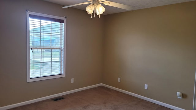 carpeted spare room with visible vents, a ceiling fan, and baseboards