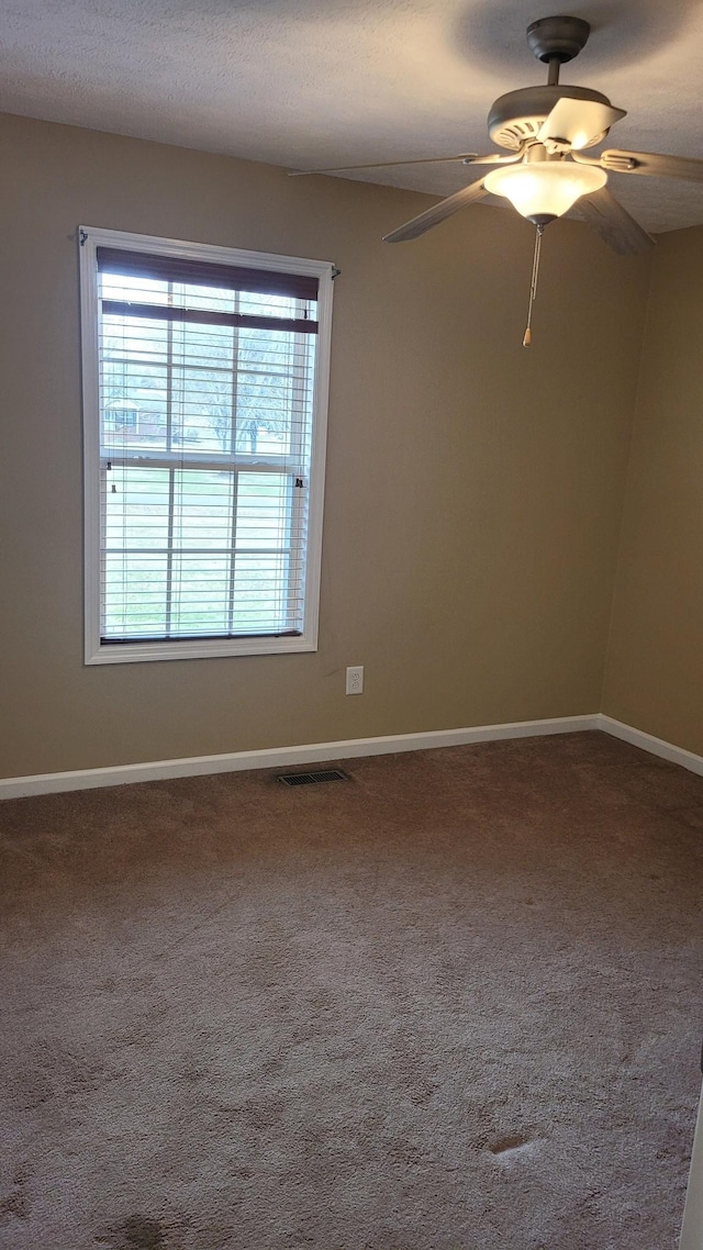 spare room featuring visible vents, a textured ceiling, carpet flooring, baseboards, and ceiling fan