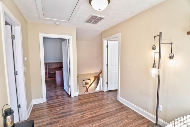 unfurnished bedroom with baseboards, visible vents, dark wood-type flooring, a spacious closet, and a textured ceiling