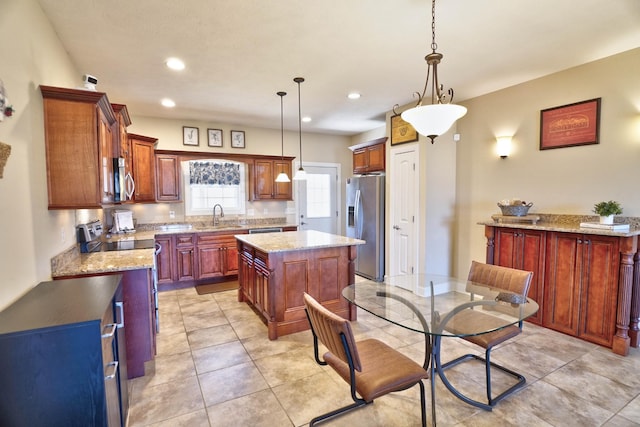 kitchen with hanging light fixtures, a kitchen island, stainless steel appliances, and a sink