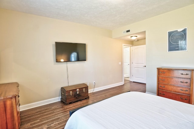 bedroom featuring visible vents, baseboards, a textured ceiling, and dark wood finished floors