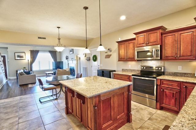 kitchen featuring light tile patterned floors, open floor plan, appliances with stainless steel finishes, and light stone countertops