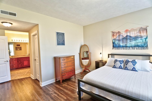 bedroom featuring dark wood finished floors, visible vents, a textured ceiling, and baseboards