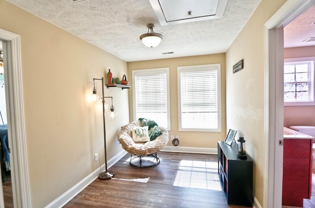 sitting room featuring visible vents, a textured ceiling, baseboards, and wood finished floors