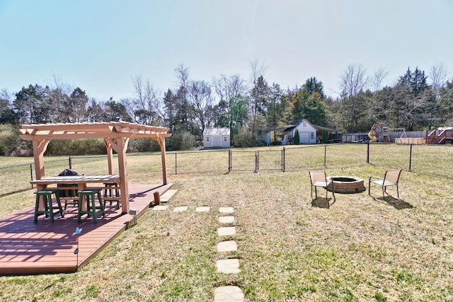 view of yard with a pergola, a fire pit, a deck, and fence