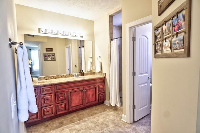 full bath with visible vents, a textured ceiling, and vanity