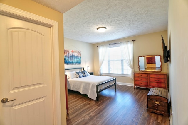 bedroom with dark wood-style floors, baseboards, and a textured ceiling