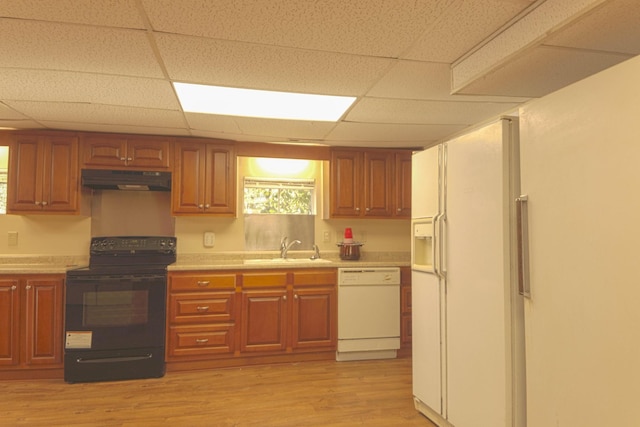 kitchen featuring a sink, under cabinet range hood, white appliances, light wood-style floors, and light countertops