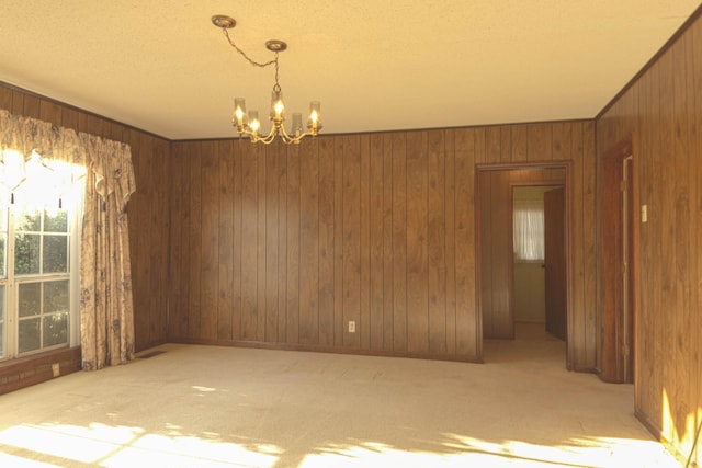 spare room with wooden walls, an inviting chandelier, and carpet floors