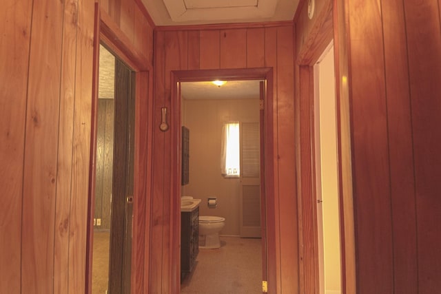 hallway featuring light colored carpet and wood walls