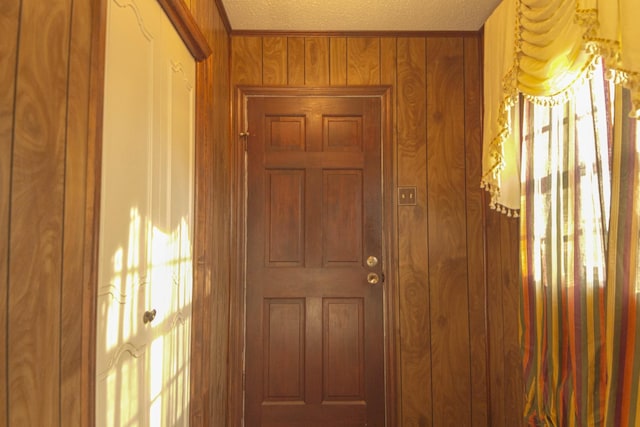 doorway to outside featuring wood walls and a textured ceiling