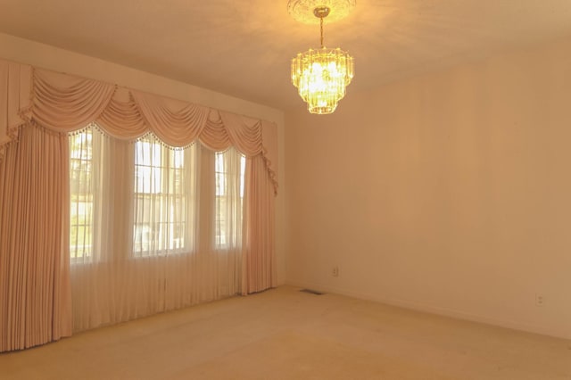 carpeted empty room with a chandelier, visible vents, and baseboards