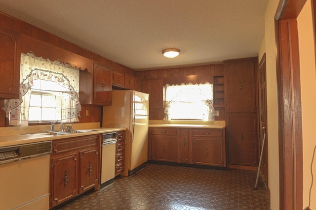 kitchen featuring dishwasher, light countertops, freestanding refrigerator, and a sink