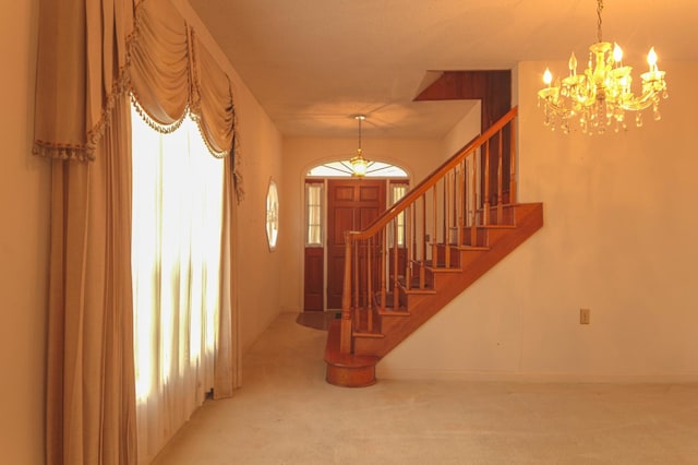 carpeted entryway featuring stairway and a chandelier