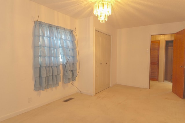 empty room with a notable chandelier, visible vents, and carpet